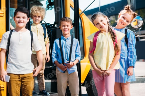 Preview: group of happy pupils looking at camera in front of school bus