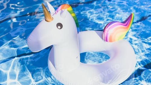 Preview: Inflatable colorful white unicorn at the swimming pool. Vacation time in the swim pool with toys