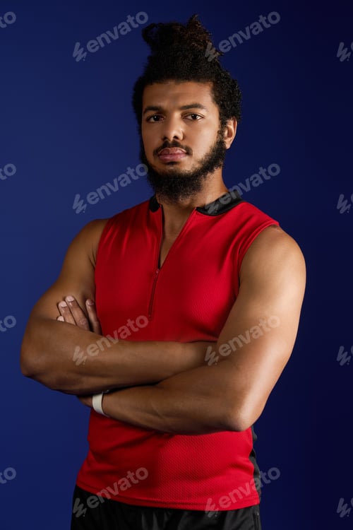 Preview: Sportive athletic man with curly hair showcases strength against blue backdrop
