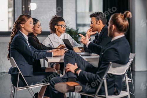 Preview: young coworkers in formalwear arguing at business meeting in office, business team meeting
