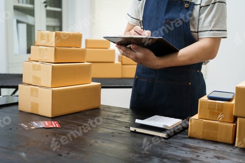 Preview: A man is working at his desk, preparing parcel boxes for shipment. He checks packs items carefully