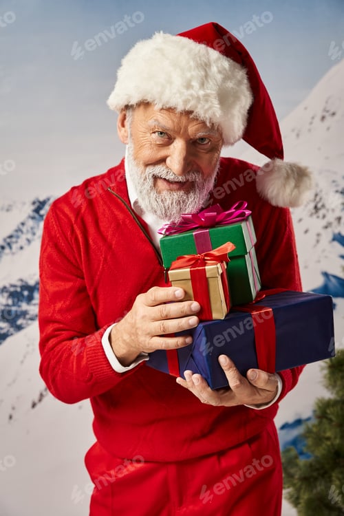Preview: cheerful bearded man dressed as Santa with christmassy hat holding pile of gifts, winter concept
