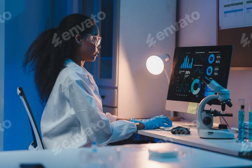 Preview: Young scientist analyzing data on computer in modern laboratory at night