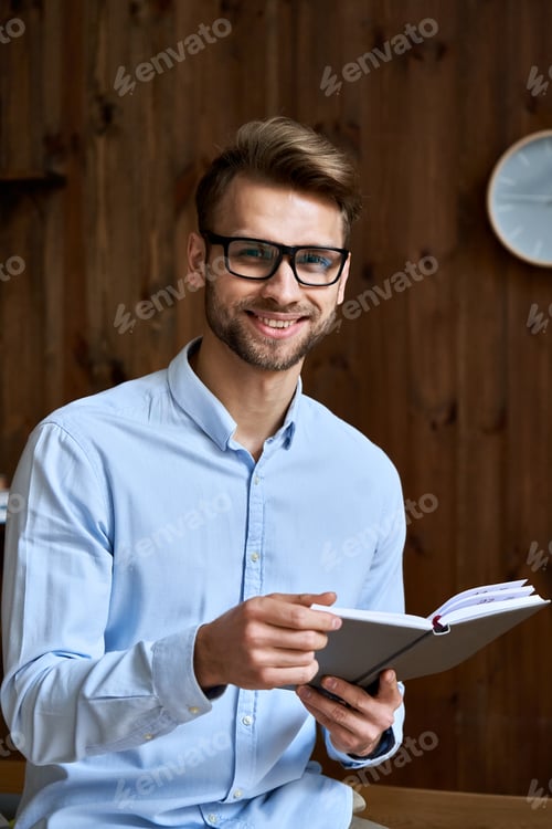Smiling Man with Glasses Holding Open Notebook