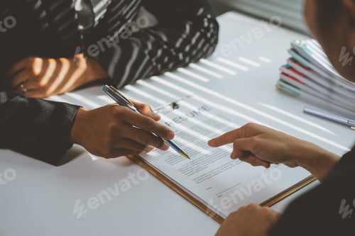Preview: Employer pointing at a resume while holding a pen, engaging in a job interview with a candidate. Ana