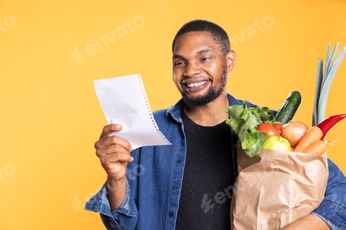 Preview: Young adult smiling while he verifies his shopping list on camera