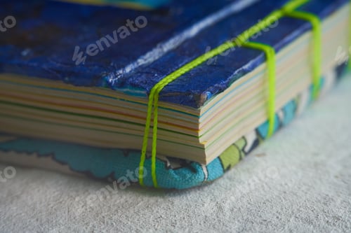 Preview: Closeup shot of folded paper sheets bound with green thread