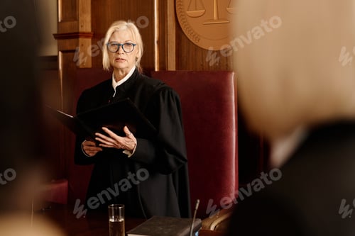 Preview: Confident female judge in eyeglasses and black mantle announcing verdict