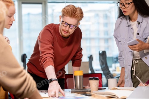 Preview: Confident young businessman pointing at financial paper during discussion