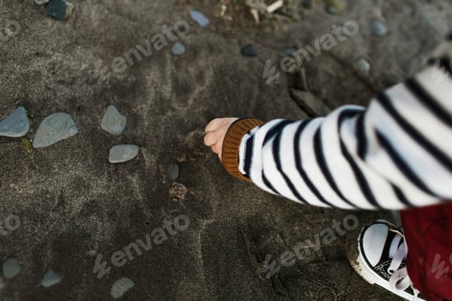 Preview: Cropped view of baby boy on beach picking up pebbles