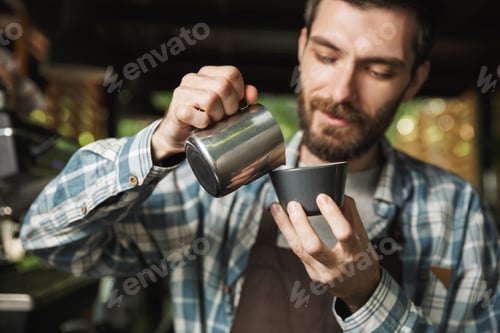Preview: Image of unshaved barista man making coffee while working in caf