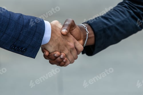 Preview: closeup of black African American businessman in suit shaking hands with Caucasian businessman