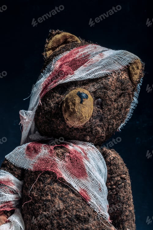 Preview: Old brown teddy bear wrapped in bloody bandages on a black background