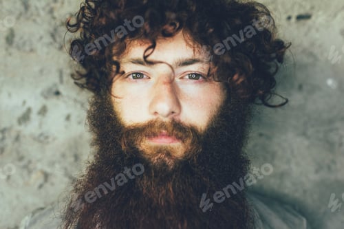 Preview: Close up portrait of young male hipster with brown curly hair and beard