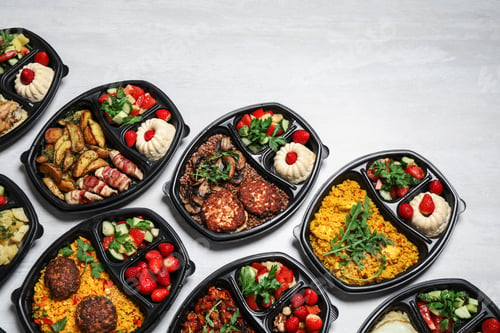 Preview: Lunchboxes with different meals on white table, flat lay. Healthy food delivery