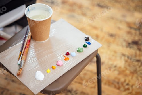 Preview: Artist's workspace featuring a palette with various paint colors, brushes