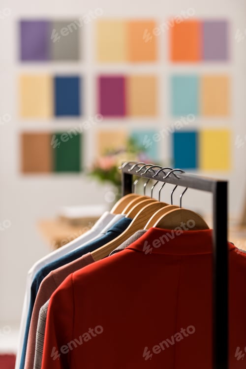 Preview: fashionable clothes on hangers in modern office