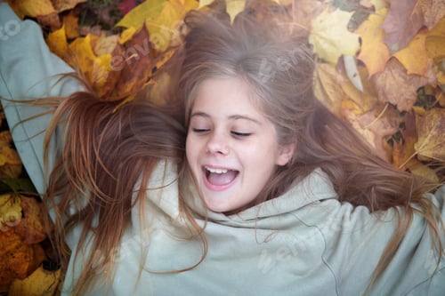 Preview: Smiling happy girl portrait, lying in autumn leaves. Outdoor.