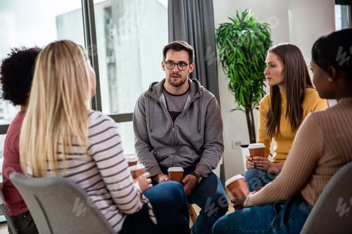 Preview: Diverse group of people sitting in circle in group therapy session.