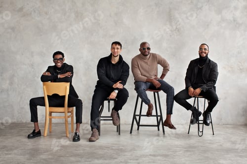 Preview: Four Men Fashionably Dressed Sitting on Chairs
