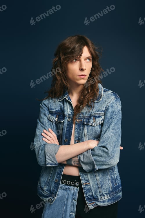 Preview: Fashionable young man exudes confidence in trendy denim against a bold background