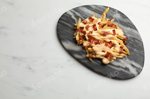 Preview: Delicious French fries with bacon and cheese sauce on white marble table, top view. Space for text