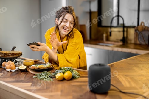 Preview: Woman speaking to a smart speaker during a breakfast at home