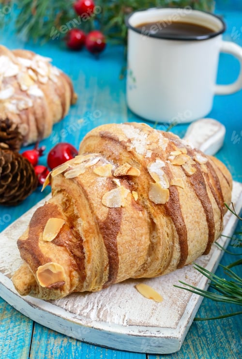 Preview: Croissants with almond flakes, coffee mug on a blue wooden background.