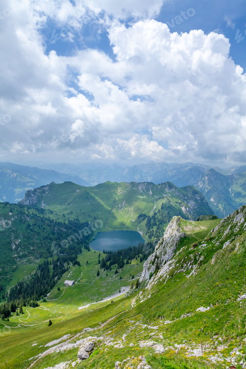 Preview: Panoramic view of lake, green alpine meadows and mountains