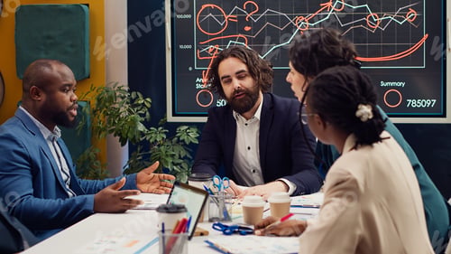 Preview: Startup team evaluating infographics data in an executive meeting,
