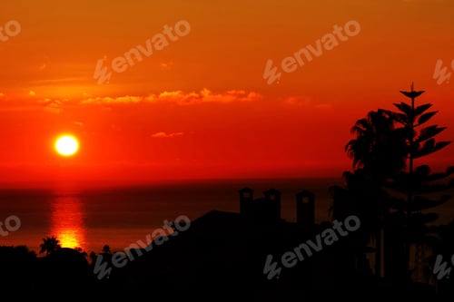 Preview: Dramatic Sunset Over Ocean with Silhouetted Coastline