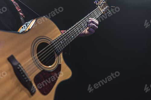 Preview: Guitarist playing acoustic guitar in the dark.