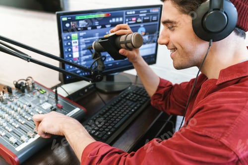 Preview: Image of young happy dj man wearing headphones working at radio station