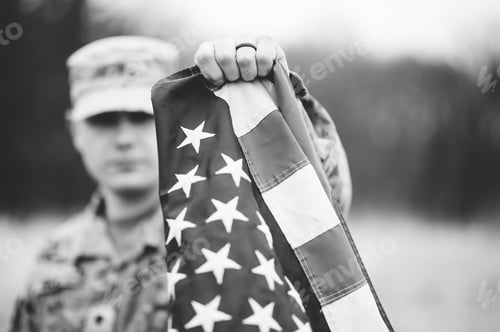Preview: Shallow focus shot of an American soldier holding the American flag