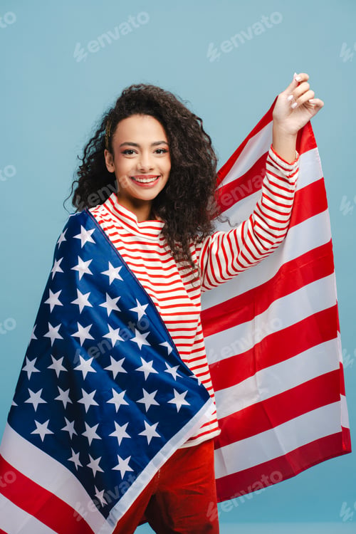 Preview: Vertical portrait of happy, smiling girl, teenager holding in American flag, rejoicing in victory