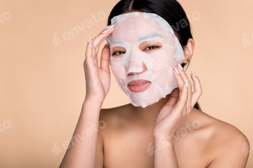 Preview: Facial care procedures. Close-up of young asian woman applying cotton facial moisturizing mask on