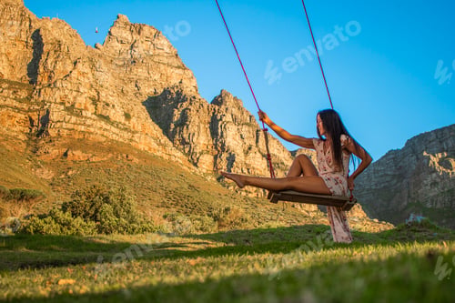 Preview: Beautiful healthy woman on a swing smiling in front of Table Mountain, Cape Town.