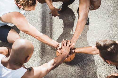 Preview: Overhead View of Basketball Team Holding Hands on Basketball Ball on Court