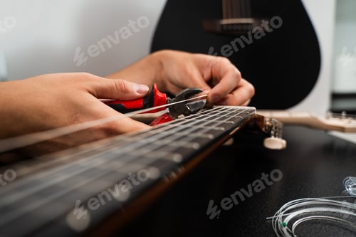 Preview: Performer cuts new nylon strings with pliers during classical restringing. Trimming