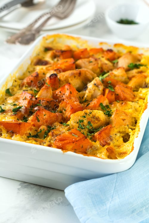Preview: Baked pumpkin with chicken, spices and cream sauce in a white ceramic form on a light background. Se