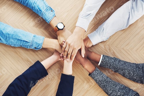 Preview: High angle shot of a group of unidentifiable businesspeople joining their hands together in unity