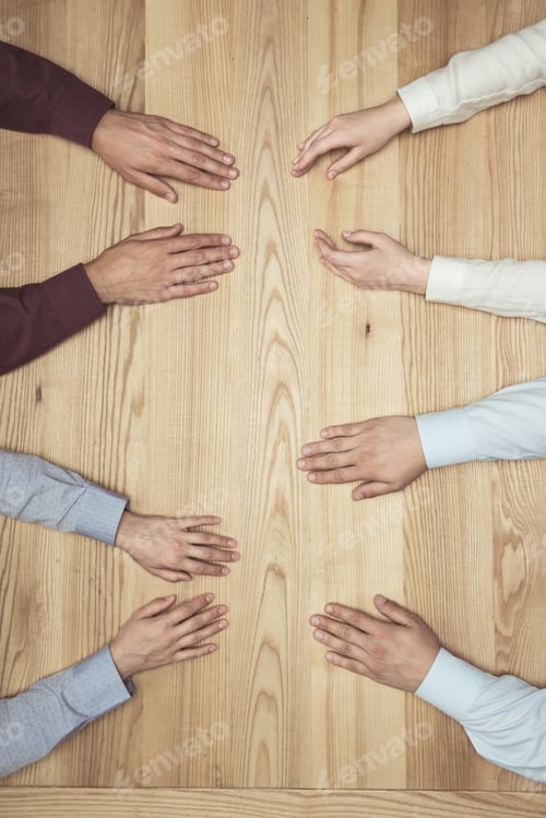 Preview: top view of hands of businesspeople on meeting on wooden tabletop