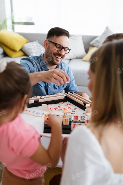 Preview: Happy young parents and children having fun, playing board game at home