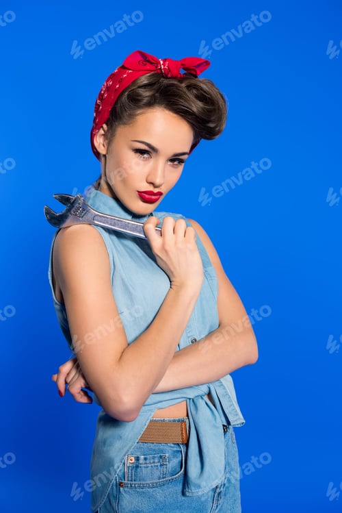 Preview: fashionable young woman in pin up style clothing with wrench isolated on blue