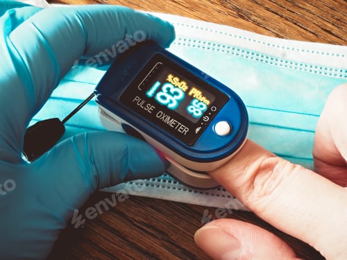 Preview: Closeup shot of a nurse using pulse oximeter for a patient with a protective face mask on the table