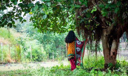 Preview: Happy Indian woman near banyan tree