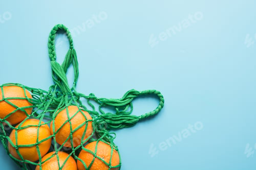 Preview: Zero waste concept. Green shopping bag with orange. Space for text.