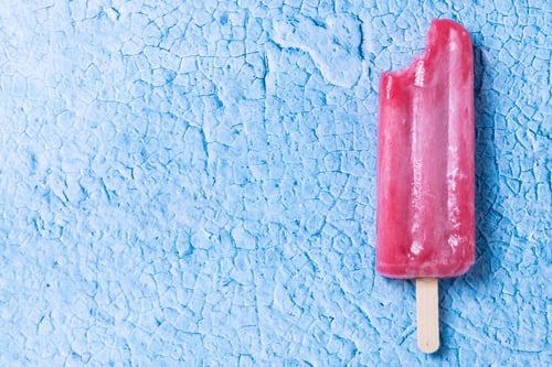 Preview: Red strawberry popsicles on blue background. Close up