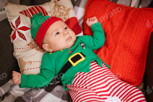 Preview: Christmas concept little boy cheerful elf looking up lies on multi-colored