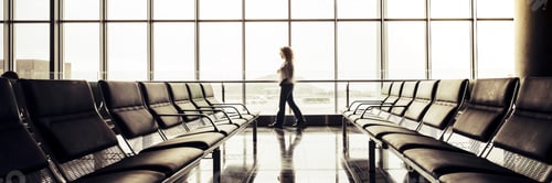 Preview: Woman walking alone in an empty airport waiting gate in departures area. people travel